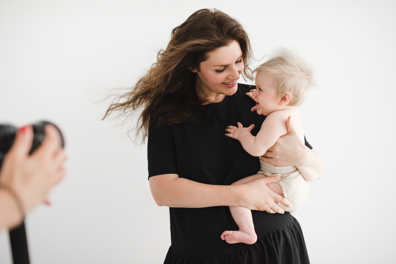 behind the scenes foto einer fotografin im studio mit kundin und baby